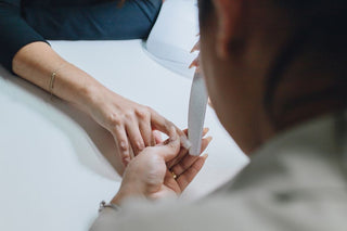 Hand using an 80-grit nail file on a hard gel manicure, demonstrating proper cross-hatch technique